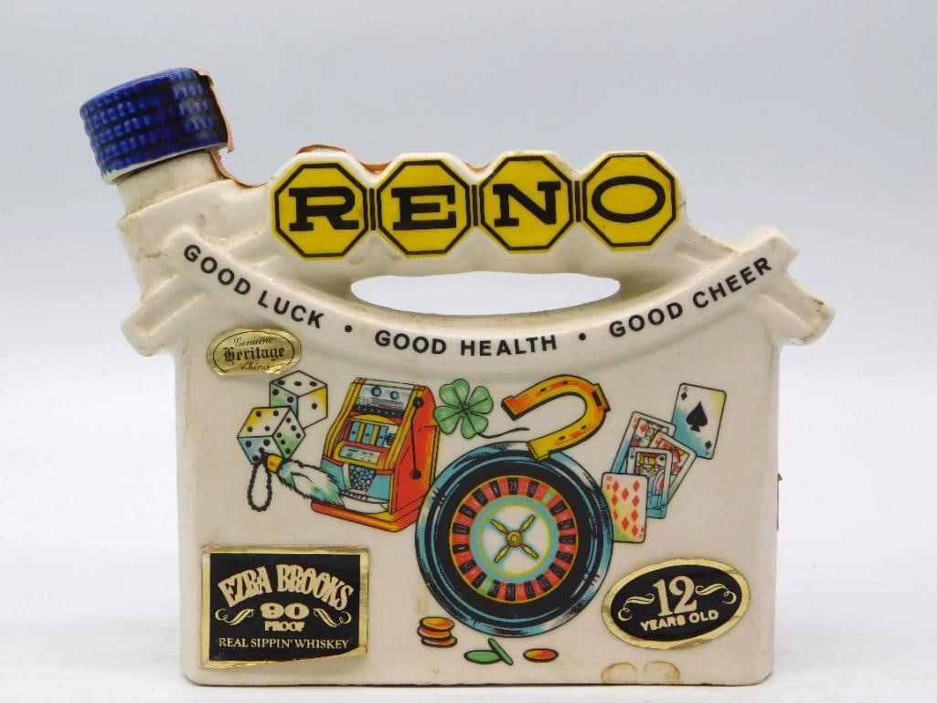 Ezra Brooks Reno Nevada Good Luck Gaming: An Ezra Brooks decanter shaped as a satchel lettered RENO across the top with Good Luck, Good Health, Good Cheer beneath. The face is painted with dice, a slot machine, clover, horseshoe, roulette