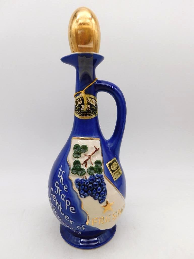 Ezra Brooks Fresno Grape Center of: An Ezra Brooks ewer in deep cobalt with a gilt teardrop stopper, the body raised with the state of California, a cluster of grapes, and the legend The Grape Center of California, Fresno. The neck tag