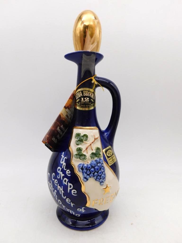 Ezra Brooks Fresno Grape Center of: A handsome Ezra Brooks ewer in deep cobalt with a gold-luster stopper, the face raised with a map of California, a heavy bunch of grapes and the legend The Grape Center of California, Fresno. Hand