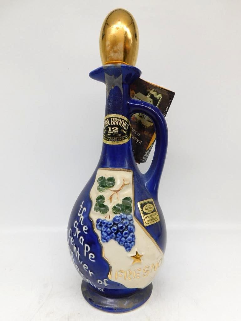 Ezra Brooks Fresno Grape Center of the: An Ezra Brooks ewer in deep cobalt, the front raised with the state of California, a golden star at Fresno and a heavy cluster of grapes on the vine, lettered The Grape Center of the World. The gold