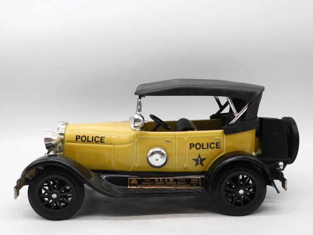 Jim Beam Police Car Ceramic Decanter: A well-turned Jim Beam decanter cast as an early open touring car pressed into police service, painted bright yellow with black lettering and a star upon the door. Bright lamps, a spare tire, and a fo