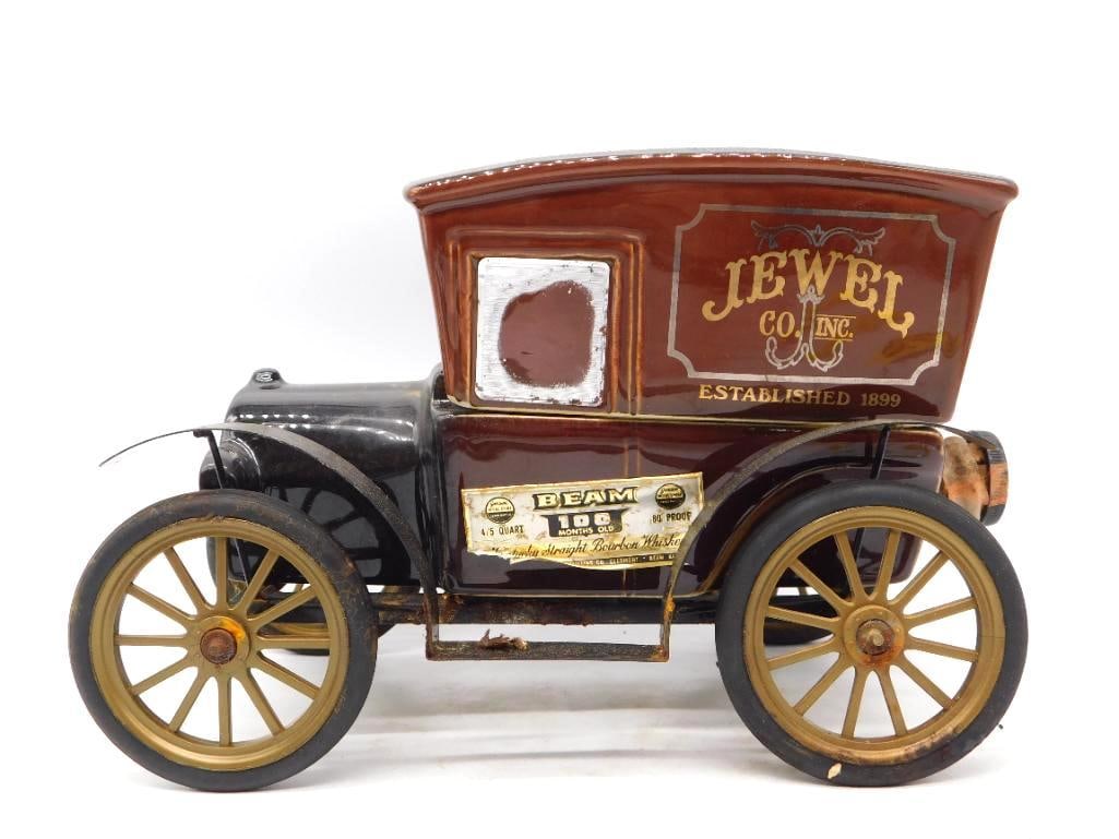 Jim Beam Jewel Co. Inc. Delivery Truck: A Jim Beam decanter modeled as an early enclosed delivery truck, the maroon van body lettered Jewel Co., Inc., Established 1899 in gilt, the hood and fenders glazed black. Gold-spoked wheels with