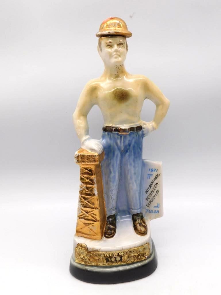 Jim Beam Tulsa Oil Capital 1971: A Jim Beam ceramic decanter modeled as an oil field roughneck standing beside his derrick, struck for the 1971 International Petroleum Exposition at Tulsa, Oklahoma. The base carries the inscription