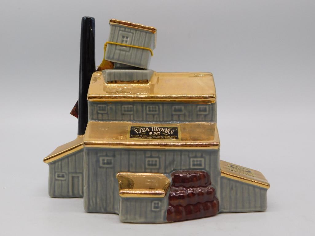 Ceramic Hometown Building Decanter: A hand-painted ceramic decanter modeled as a small gray hometown building with a brown chimney and rooftop antenna, in the style of a landmark or firehouse series decanter. No maker's mark is visible
