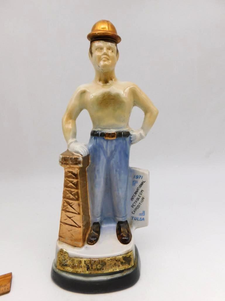 Jim Beam Tulsa Oil Capital 1971: A Jim Beam Genuine Regal China decanter sculpted as a shirtless oil driller in his hard hat, standing beside a gold-detailed derrick and marked 1971 International Petroleum Exposition, Tulsa - Oil