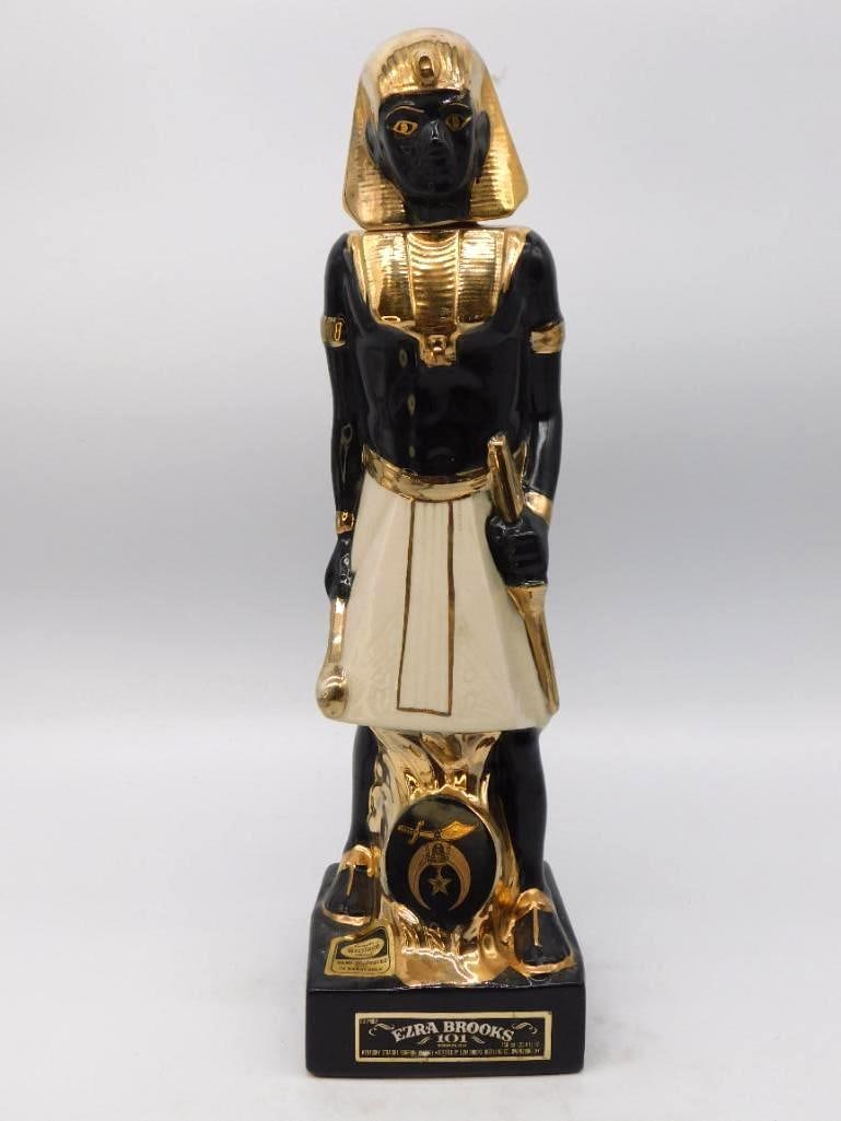 Ezra Brooks Shriners Imperial Council: A stately Ezra Brooks decanter modeled as an Egyptian pharaoh in black and gold, the Shrine crescent and scimitar set upon the shield at his feet. The gilding is bright and the modeling crisp, no