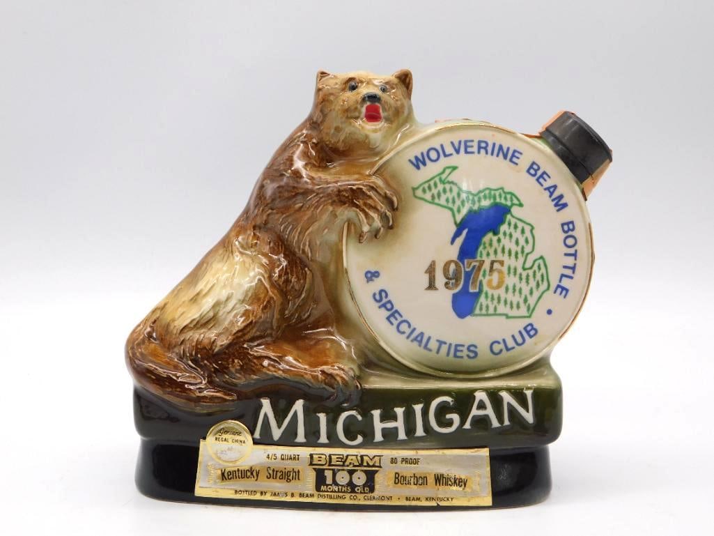 Jim Beam Michigan Wolverine Beam Bottle: A Regal China decanter for Jim Beam, cast with a climbing wolverine set beside a Michigan state medallion. Marked Wolverine Beam Bottle and Specialties Club 1975, with informational text printed to th