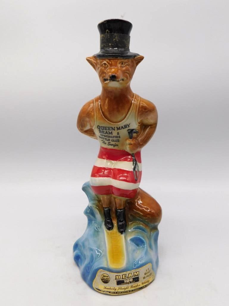 Jim Beam Queen Mary Bottle Club The: A jaunty Jim Beam Regal China decanter modeled as a top-hatted fox in a striped bathing costume, seated on a curl of blue surf with a small bottle in hand. The vest reads Queen Mary Beam & Specialties