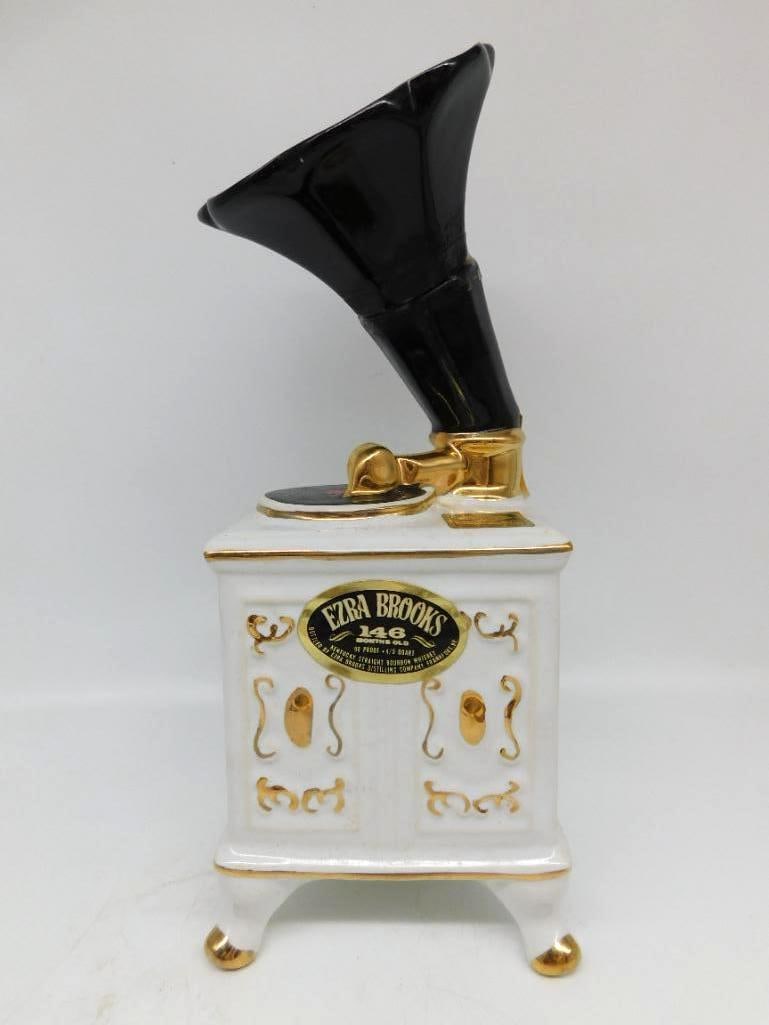 Ezra Brooks Gold Gramophone Phonograph: An Ezra Brooks white porcelain decanter modeled as an antique gramophone, the black horn rising above a cabinet on feet, with gilt accents throughout. Carries the 146 Months Old label and stands