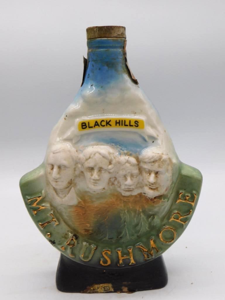 Jim Beam Bacchus Grapevine Decanter: A Jim Beam Regal China decanter bearing a relief bust of Bacchus, the Roman god of wine, upon a barrel-form body dressed in blue and green grapevine and grape clusters against copper luster. Marked
