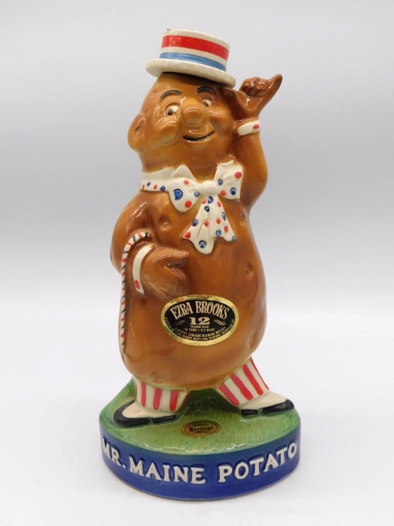Ezra Brooks Mr. Maine Potato Character: An Ezra Brooks 12-Year-Old bourbon decanter sculpted as Mr. Maine Potato, a whimsical fellow in top hat and bow tie standing upon a blue base lettered Maine Potato. Approximately 12 inches long as