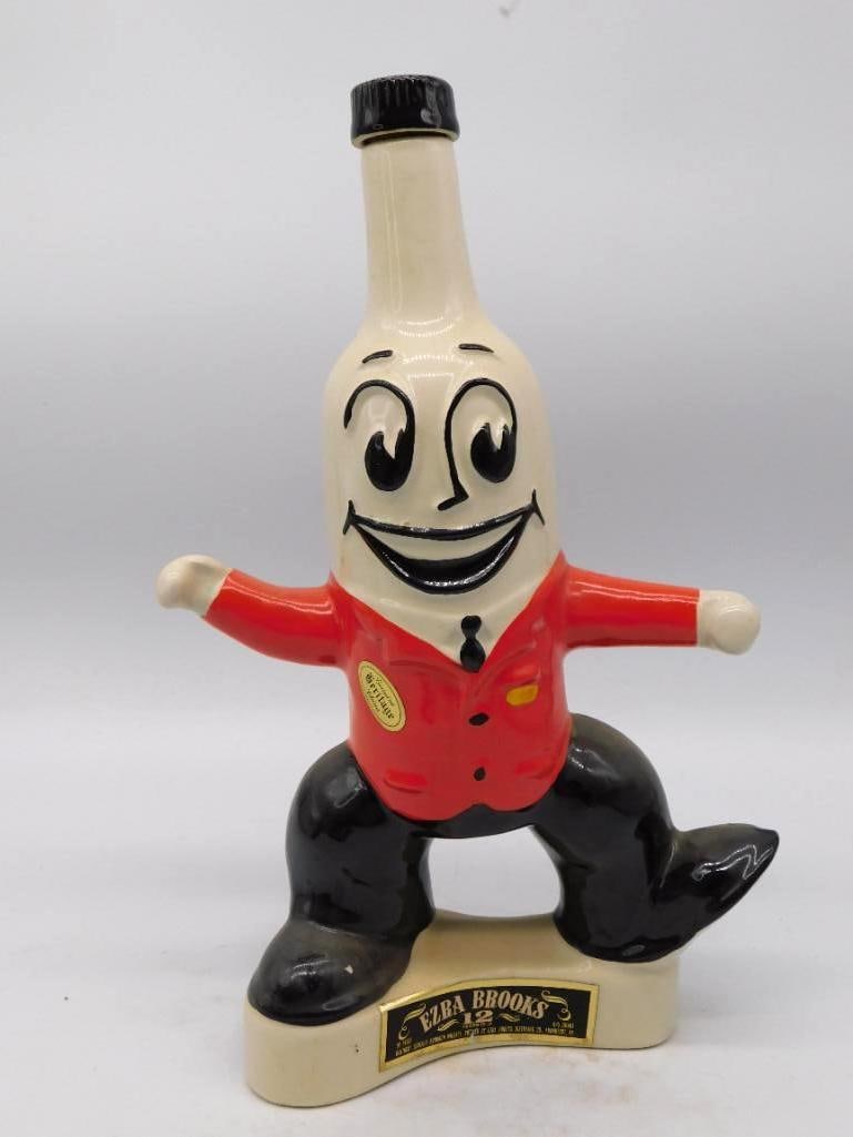 Ezra Brooks Foremost Man Novelty Bottle: An Ezra Brooks decanter modeled as a grinning bottle-man in red vest and black trousers, arms flung wide and feet planted square. A jaunty bit of mold-making, the painted face lively and the glaze