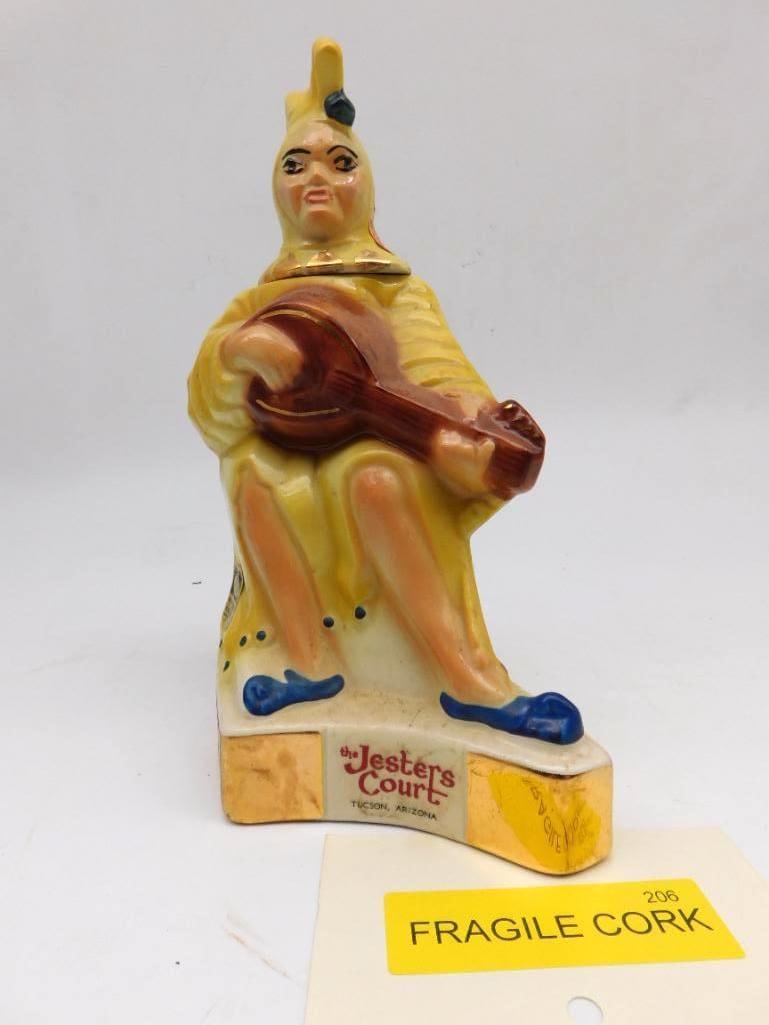 Jesters Court Tucson Arizona Jester: A ceramic decanter modeled as a jester in a yellow robe at his lute, the second example of the piece in this collection. Marked The Jesters Court, Tucson, Arizona. The lot card is tagged Fragile