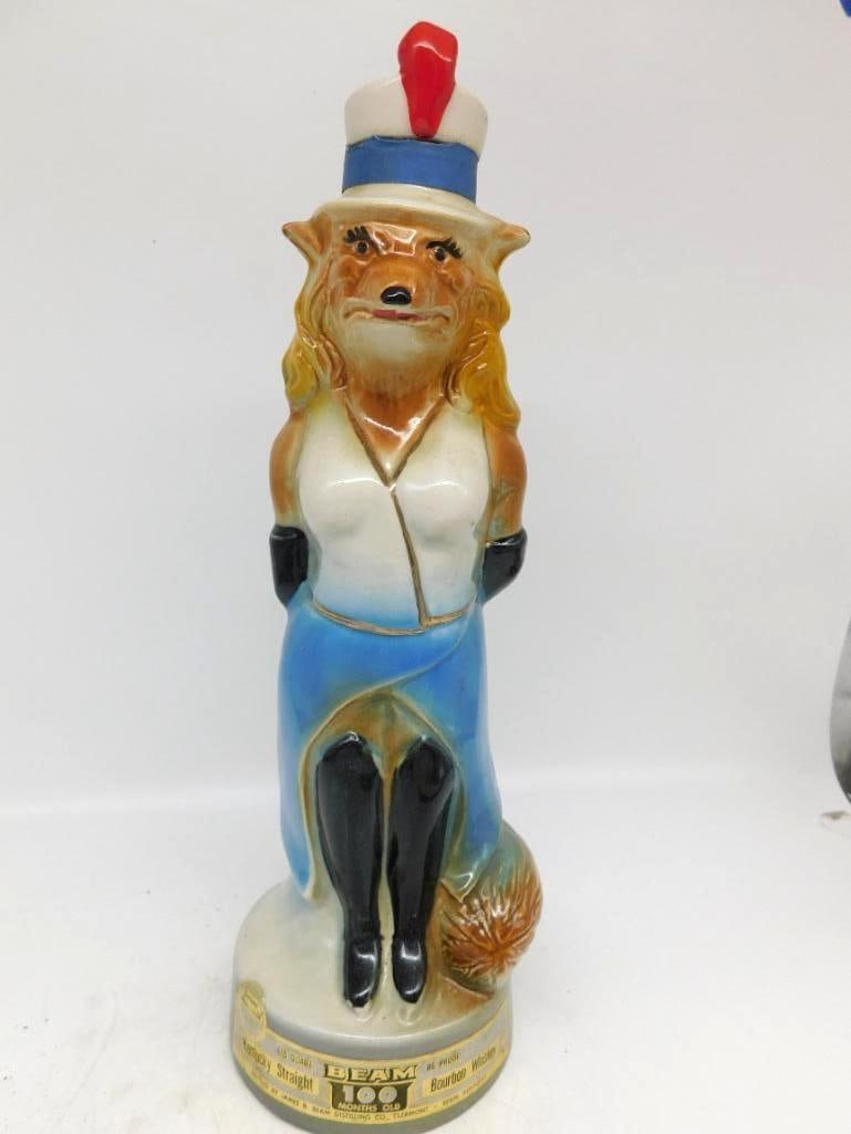 Jim Beam Regal China Fox in Evening: A jaunty Jim Beam Regal China decanter modeled as a vixen turned out for an evening, in white blouse and blue skirt with black gloves and a boater hat trimmed with a red plume. The character is drawn
