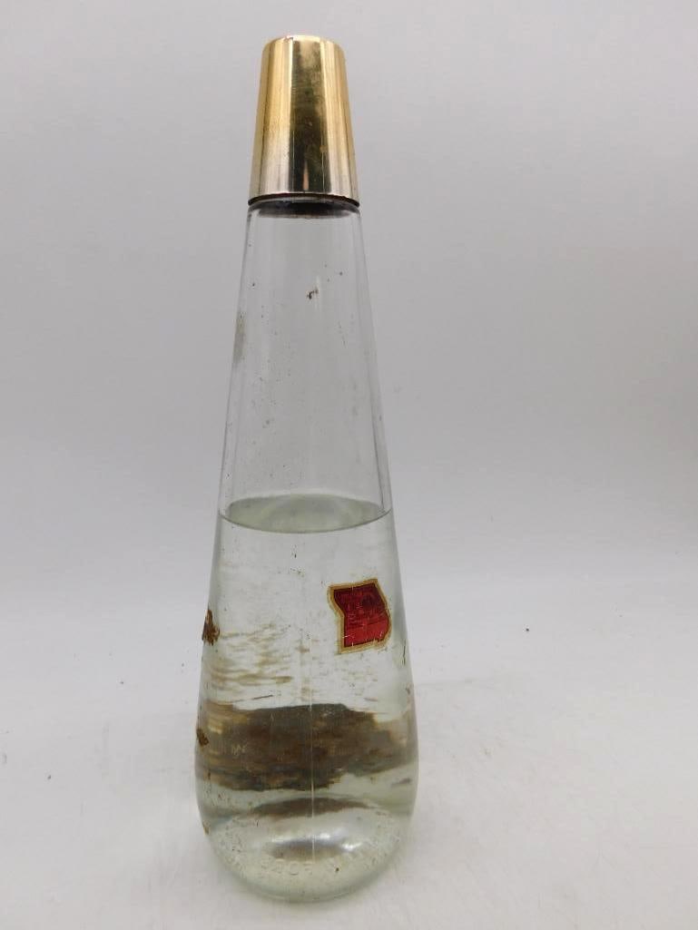 Tapered Glass Decanter with Gilt Cap: A trim tapered decanter of clear glass in conical form, unadorned save for a small red foil label at the shoulder and fitted with a gilt metal cap. No maker's mark is legible, and the piece is offered