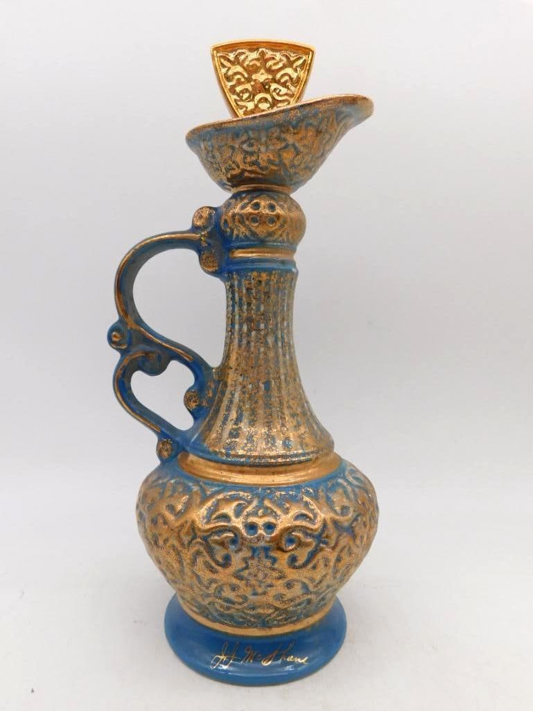 Blue and Gold Ornate Ewer Decanter with: A stately ewer decanter glazed turquoise beneath heavy gilt arabesque, the ovoid body, tapered neck and scrolled handle all worked in raised ornament. The fitted stopper repeats the pattern in bright