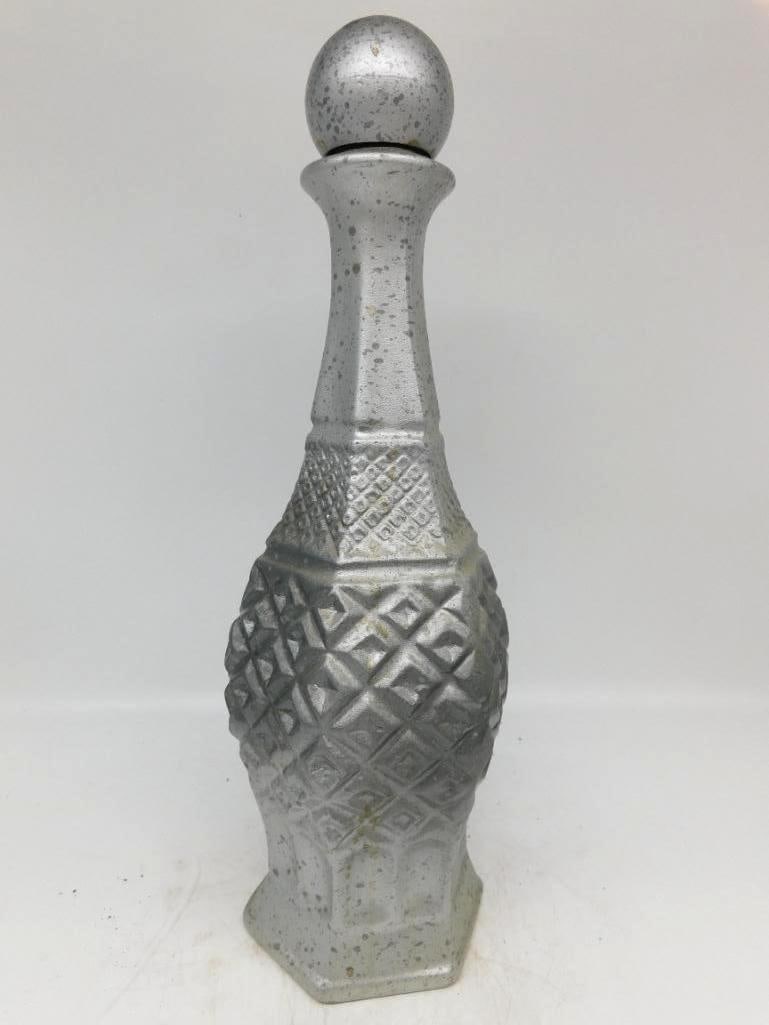 Diamond-Quilted Glass Decanter in Silver: A well-turned glass decanter of six-sided form, the body pressed in a deep diamond quilt below a tall tapered neck and a round ball stopper, the whole finished in a silvered coat. Stands