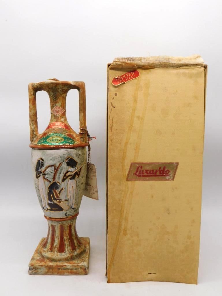 Luxardo Egyptian Amphora Cherry Wine: An uncommon Luxardo decanter of Italian make, shaped as a two-handled amphora on a fluted column base and glazed in mottled ochre and stone. The body is molded with a band of Egyptian figures picked