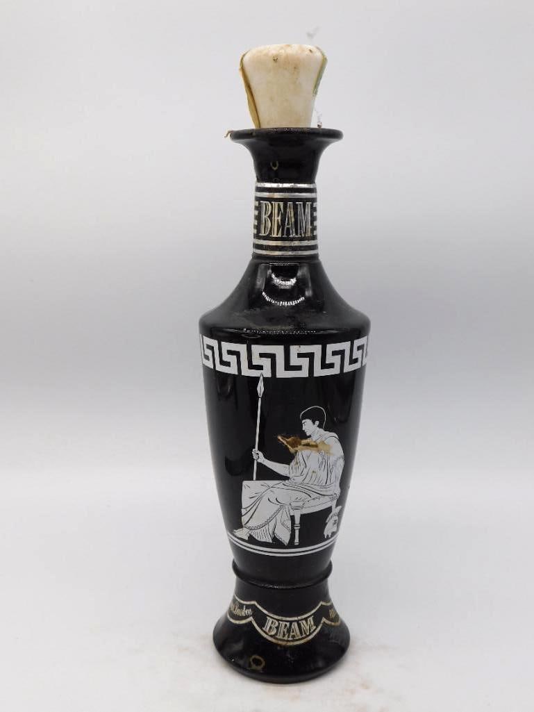 Jim Beam Black Glass Grecian Urn: A handsome Jim Beam decanter in black glass drawn after an ancient Grecian urn, a robed classical figure seated with spear rendered in white beneath a Greek key band. BEAM is lettered in gilt at both