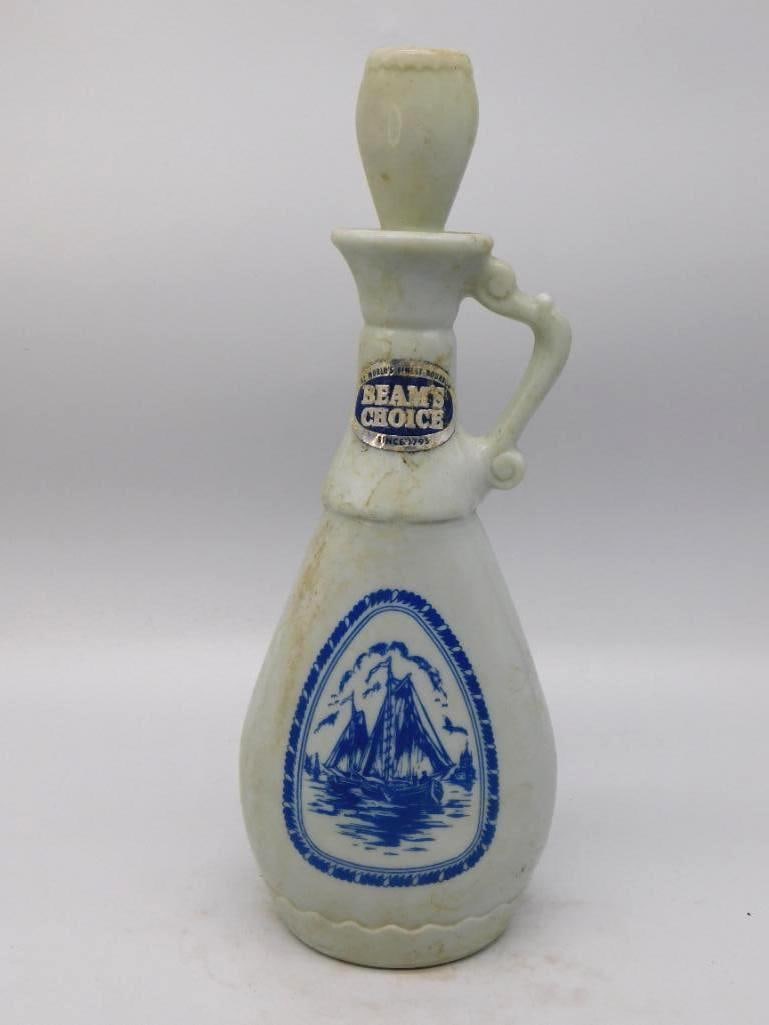 Jim Beam Beam's Choice Delft Blue: A trim Jim Beam ewer in the Delft manner, its pale body carrying a blue-printed harbor scene of a sailing ship beneath a clouded sky. A scrolled handle and slender stopper finish the piece agreeably,