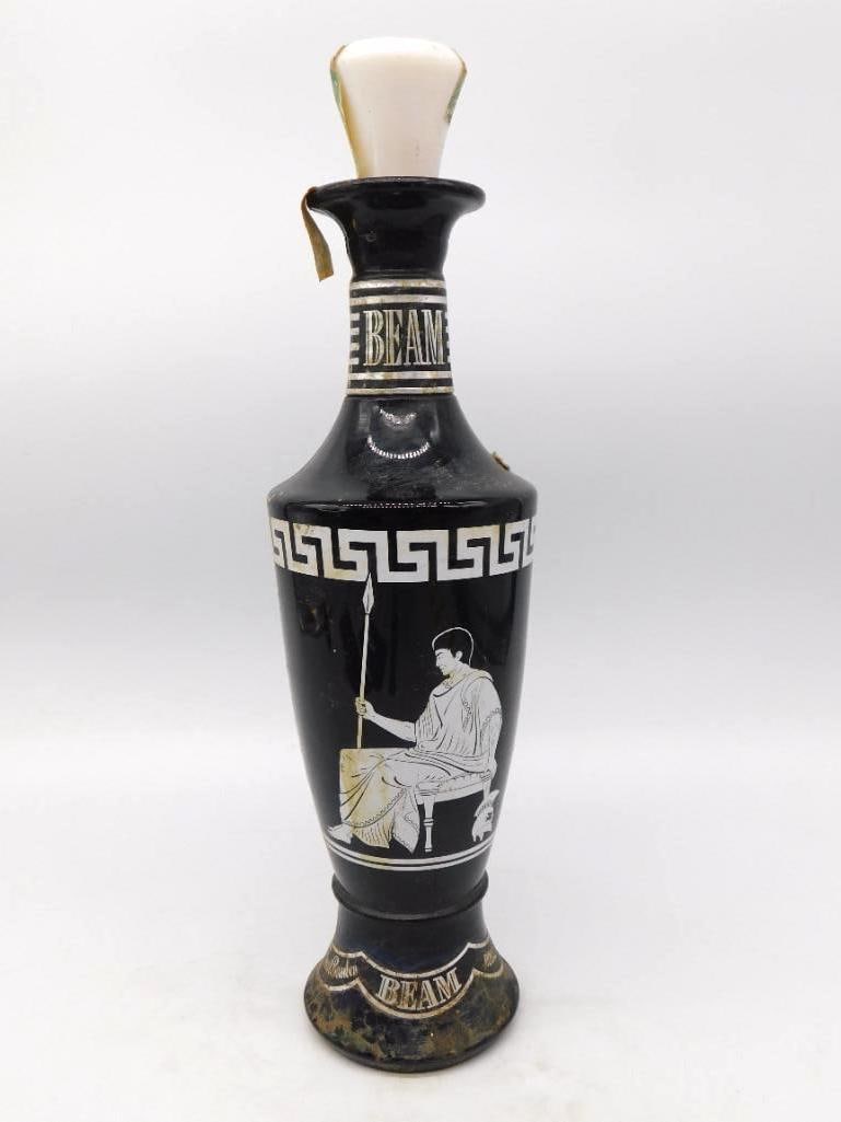 Jim Beam Black Glass Grecian Urn: A stately Jim Beam decanter in black glass after the Grecian manner, banded with a white Greek key and painted with a seated figure holding a spear. The neck collar and footed base are lettered BEAM