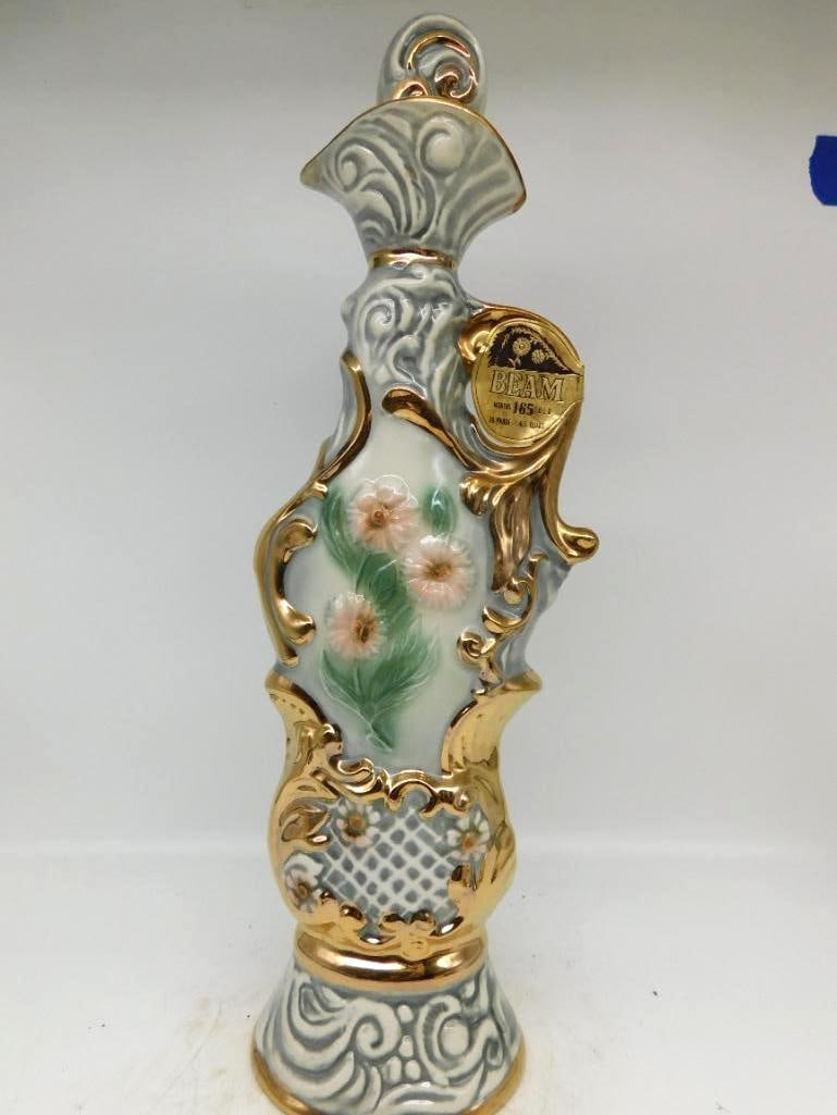 Jim Beam Regal China Gold Scroll and: A well-turned Jim Beam Regal China decanter in the ornate taste, its pale gray body molded with scrollwork and lattice and framed with heavy gold rocaille, a spray of hand-painted daisies set in the