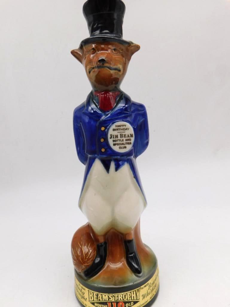 Jim Beam Trophy Fox Decanter in Blue: A James B. Beam ceramic decanter modeled as a fox dressed in a blue coat and top hat with a cane in hand, rakish as you please. The medallion reads "Happy Birthday Jim Beam Bottle and Specialties Club