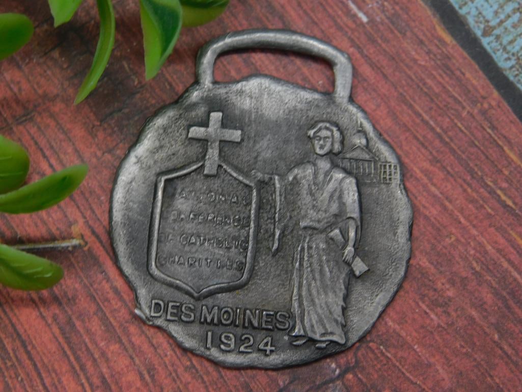 1924 Des Moines WATCH FOB VINTAGE ANTIQUE: - Metal graduation medal dated 1924. | - Features the text 'Des Moines' and the year '1924' at the bottom. | - Design includes a shield with a cross and a graduate in cap and gown holding a diploma.