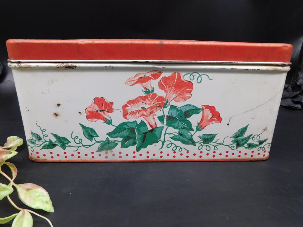 Floral-Decorated Metal Tin with Lid: Metal tin with floral decorations on all sides and a removable red lid. Features vibrant green and red flower designs. Noted signs of wear include spots of rust and scratches. The interior is unlined