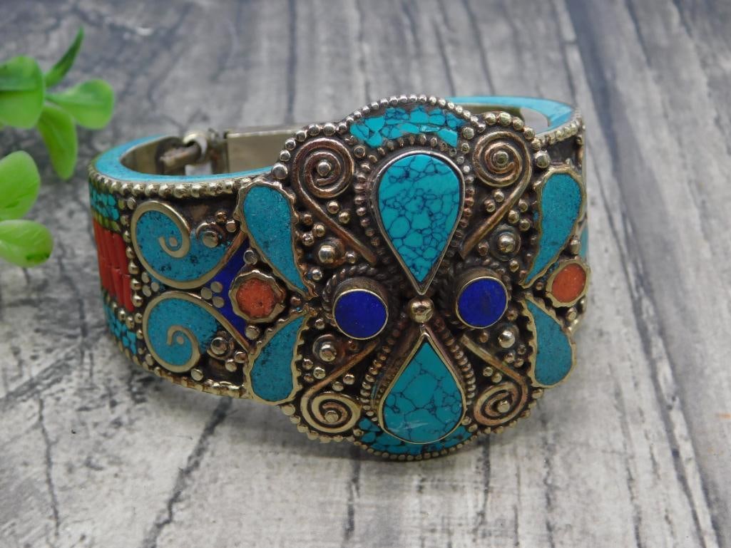 Bracelet Tibetan Turquoise Coral Enamel Cuff: Ornate Tibetan-style hinged cuff bracelet in brass-tone metal, inlaid with turquoise-colored stone, coral-colored accents, and blue enamel in a scrollwork floral motif. Fits an average wrist with a