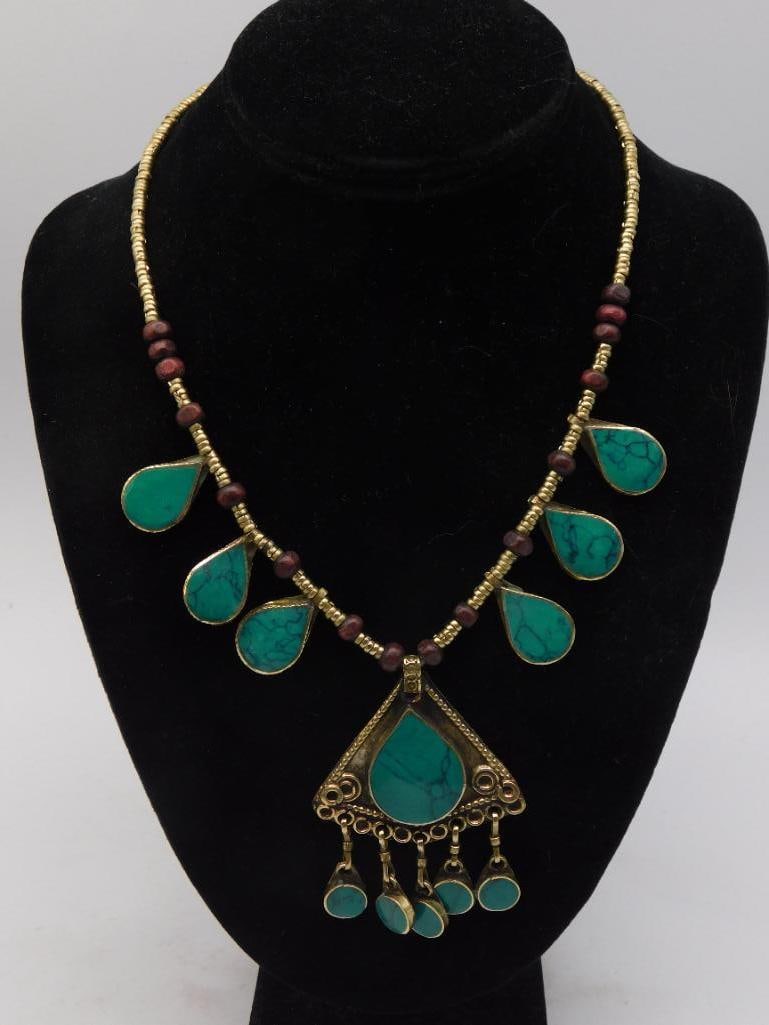 Jewelry Necklace - Tribal Turquoise-Style Teardrop Pendant: Tribal-style necklace featuring turquoise-colored teardrop stone drops set in brass, alternating with garnet-red beads and brass spacer beads, centered on a triangular pendant with matching dangles. M