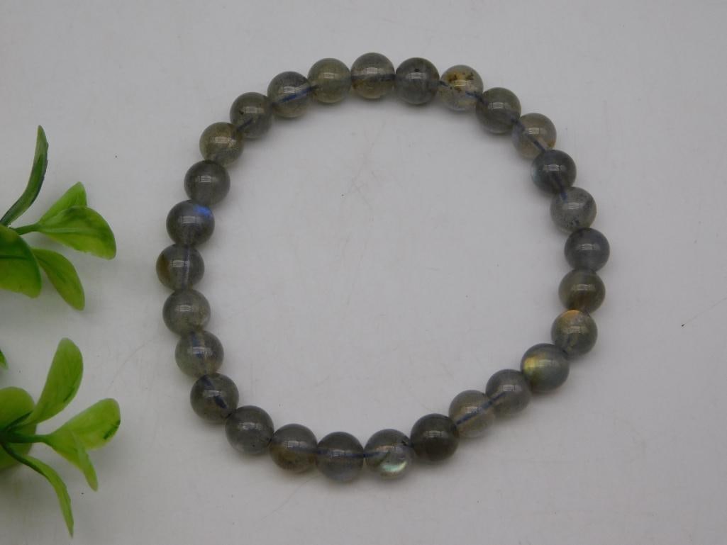 Labradorite Beaded Stretch Bracelet, Gray Flash Beads: Stretch bracelet strung with round polished labradorite beads showing gray base color and blue-gold labradorescent flash. Measures approximately 2.5 inches in diameter, shown with a quarter for scale.