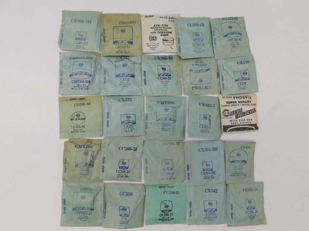 Watch Parts: Crystal Envelope Lot with Loose Lenses: Approximately 25 vintage watch crystals in original manufacturer envelopes fitted for Elgin, Bulova, Hamilton, and Waltham watches, plus several loose glass and plastic crystal lenses. A ruler photo s