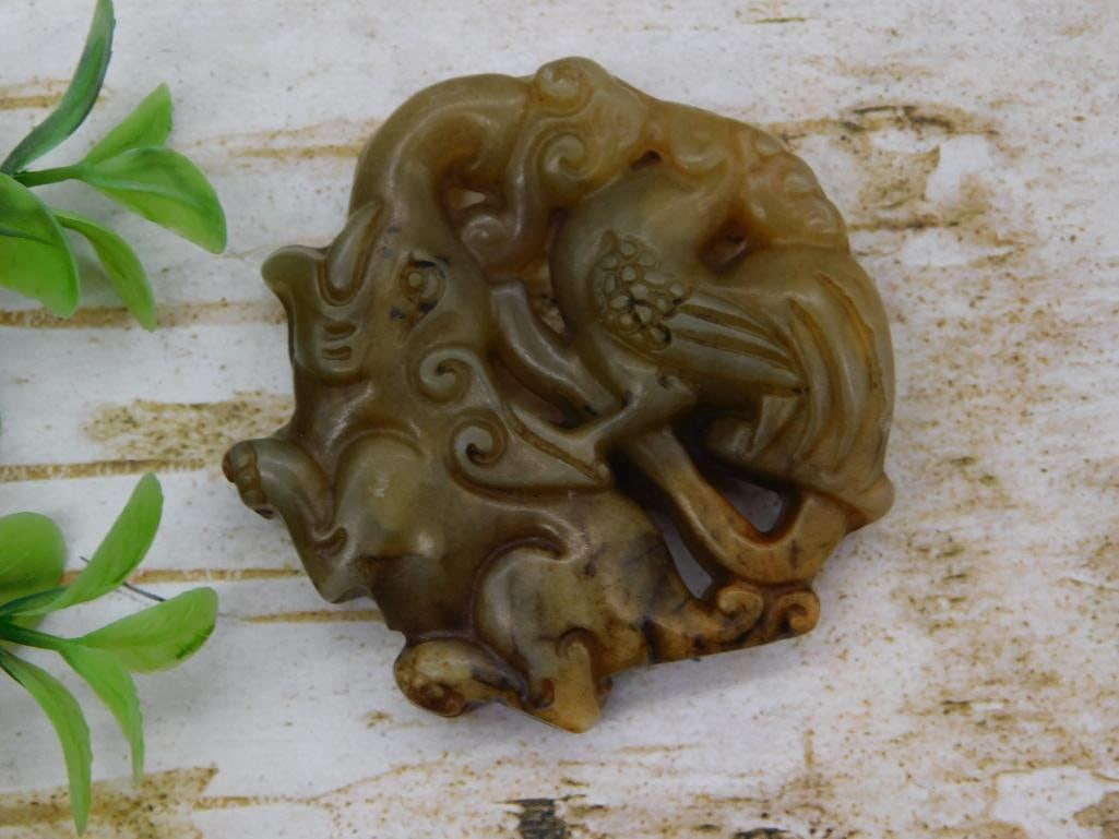 Antique - Carved Jade/Hardstone Chinese Plaque with Figural and Scroll Motif: Carved brownish-green hardstone (jade-type) plaque or belt ornament depicting a figure amid scrolling cloud and foliate motifs, likely of Chinese origin, measuring approximately 2.5 inches across.