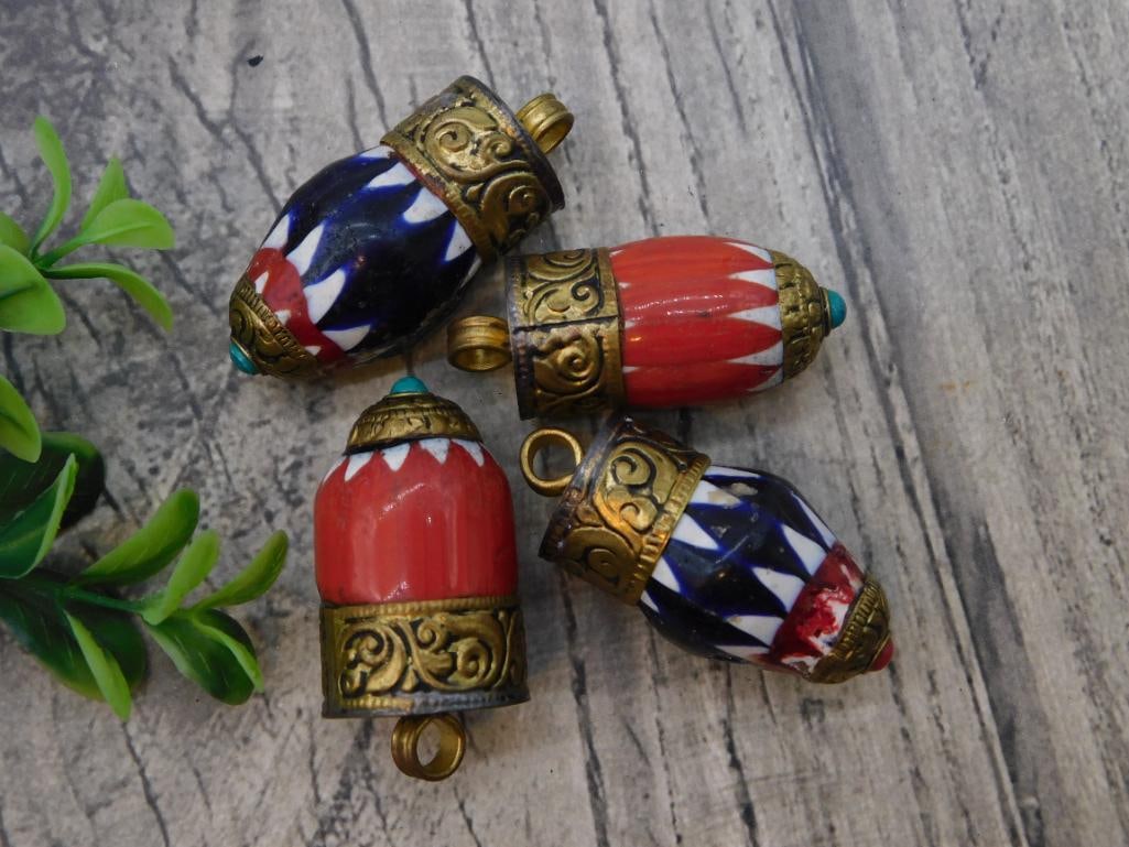 Pendant Tibetan Ghau Prayer Bead Charms Set of 4: Set of four Tibetan-style ceremonial bead pendants with hand-painted enamel triangular patterns in red, navy, and white, capped with ornate brass filigree and turquoise-colored accent stones. Each