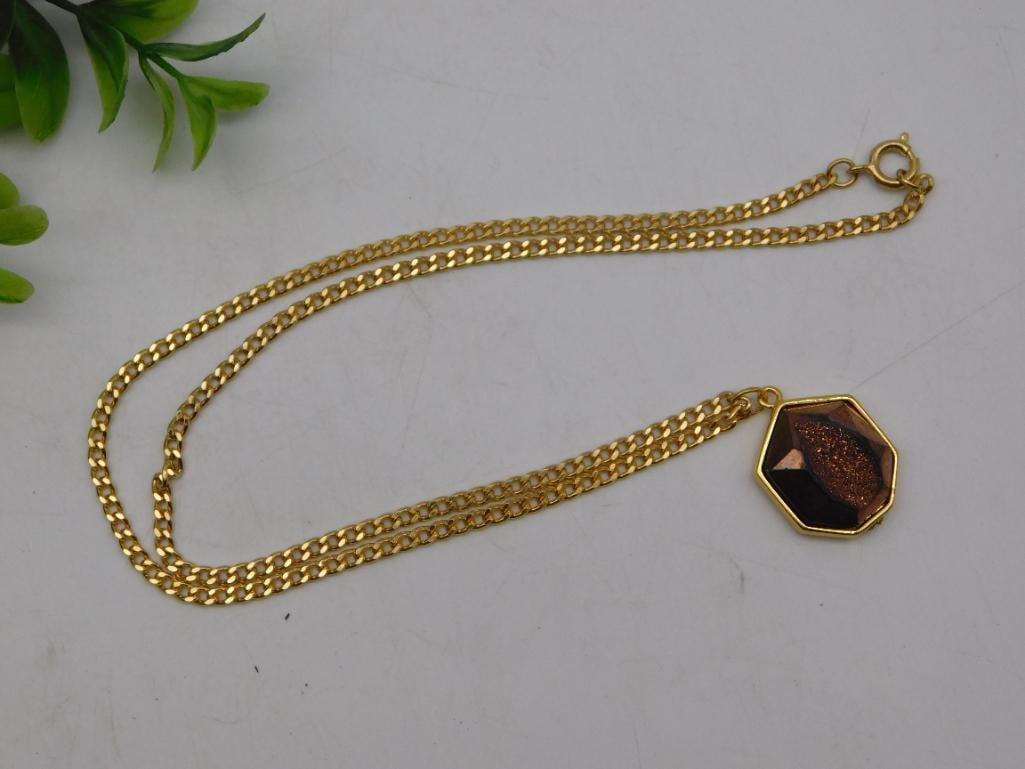 Necklace: Gold-Tone Curb Chain with Faceted Druzy Hexagon Pendant: Gold-tone curb link chain necklace with a spring ring clasp, suspending a faceted hexagon pendant bezel-set with a sparkling copper/bronze-colored druzy stone. The pendant measures approximately 1 inc