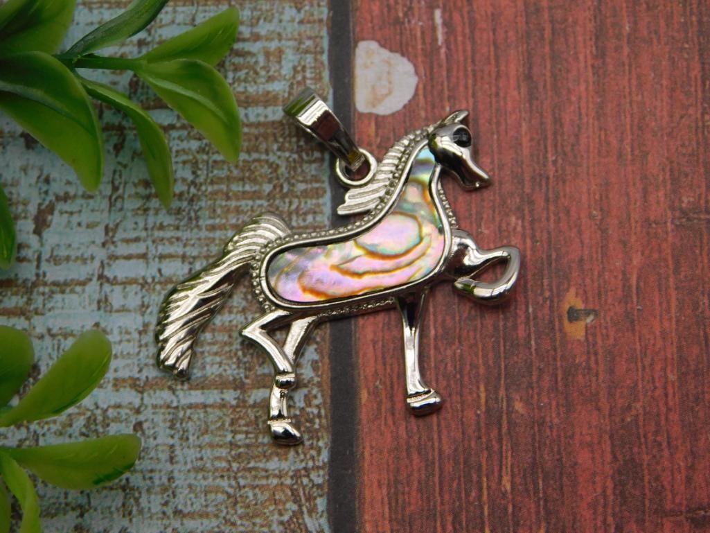 Pendant - Silver-Tone Horse Charm with Abalone Shell Inlay: Silver-tone horse-shaped pendant featuring an inlaid abalone/mother-of-pearl body panel with iridescent blue, pink, and gold hues. Measures approximately 1.5 inches long, shown next to a quarter for s