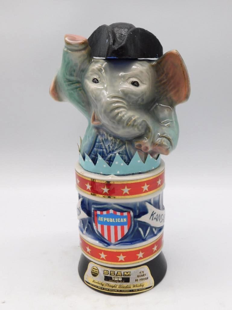 Jim Beam Nebraska Cornhuskers Football: A Jim Beam Regal China decanter with a red-hatted Cornhusker figure perched atop a brown and white football embossed Nebraska in gold. Kentucky Straight Bourbon Whiskey, the tax stamp still present.