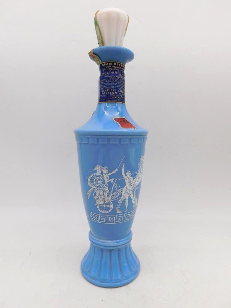 Jim Beam Olympian Blue Grecian Urn: A handsome Jim Beam Olympian decanter in the form of a Grecian urn, the sky-blue ground carrying white classical warriors and charioteers in relief above a Greek key band. The white stopper is fluted