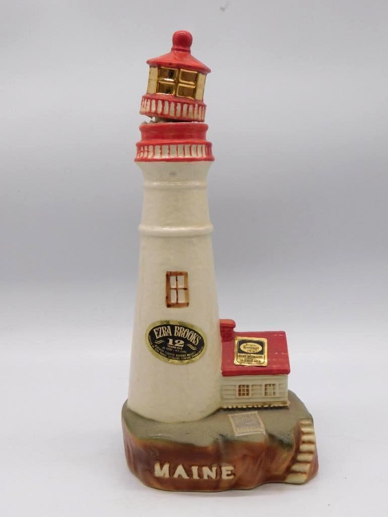 Ezra Brooks Portland Head Light Maine: An Ezra Brooks ceramic decanter shaped as the Portland Head Light of Maine, a cream tower with red trim and a gold lantern room rising from a rocky base marked Maine. Marked 12 Years Old, and it