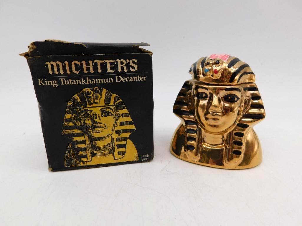 Michter's King Tutankhamun Miniature: A small Michter's decanter modeled as the funerary mask of King Tutankhamun, finished in bright gold with black striping and the vulture and cobra painted at the brow. The carton states the piece is