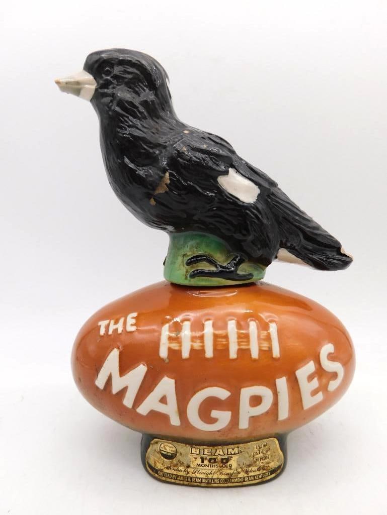 Jim Beam The Magpies Australian Football Club Decanter: A Jim Beam Regal China decanter modeled as a magpie perched upon an Australian football lettered THE MAGPIES in raised white. The bird is well cast black and white with a pale beak and the ball carrie