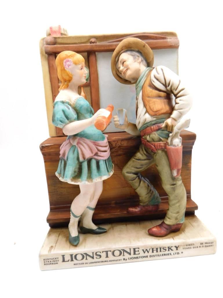 Lionstone Cowboy and Saloon Girl Kentucky Whiskey Decanter: A Lionstone Kentucky Straight Bourbon Whiskey decanter in porcelain sculpted as a cowboy with a holstered pistol standing at the bar counter beside a saloon girl in a green dress. It belongs to the sa