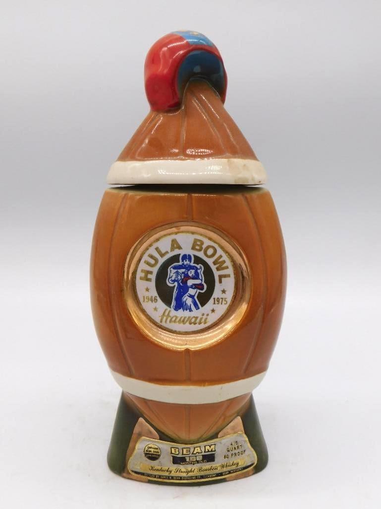 Jim Beam 1975 Hula Bowl Hawaii Football Helmet Decanter: A Jim Beam Kentucky Straight Bourbon Whiskey decanter shaped as a football helmet marking the 1975 Hula Bowl in Hawaii established 1946. A red stopper gives the piece its accent. Approximately 8