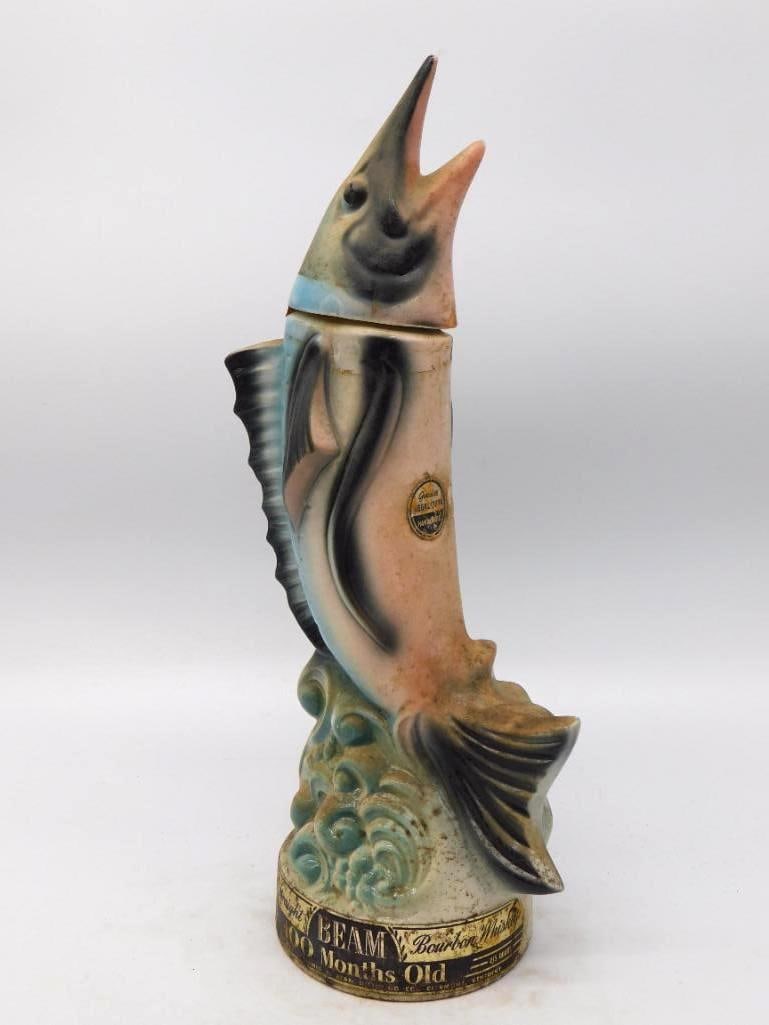 Jim Beam Leaping Blue Marlin Decanter 100 Months Old Bourbon: A spirited Jim Beam decanter modeled as a marlin breaking from the swell bill raised and dorsal fin flared. The mold-maker caught the fish in mid-leap no small feat and the curling waves at the foot a