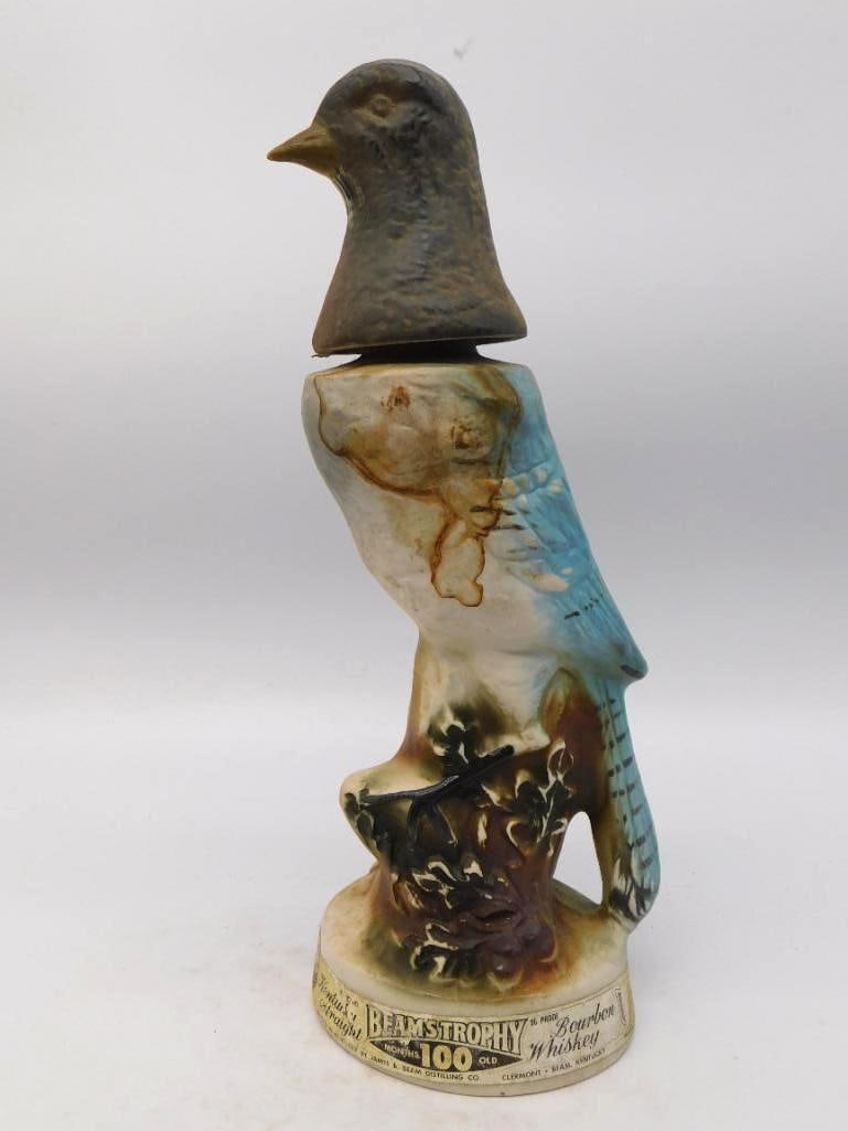 Jim Beam Blue Jay Bird Whiskey Decanter Beam's Trophy Series: A Jim Beam Regal China decanter rendered as a blue jay perched on a weathered stump the head lifting off as the stopper. The blue of the wings and tail is handsomely graded and the modeled foliage at