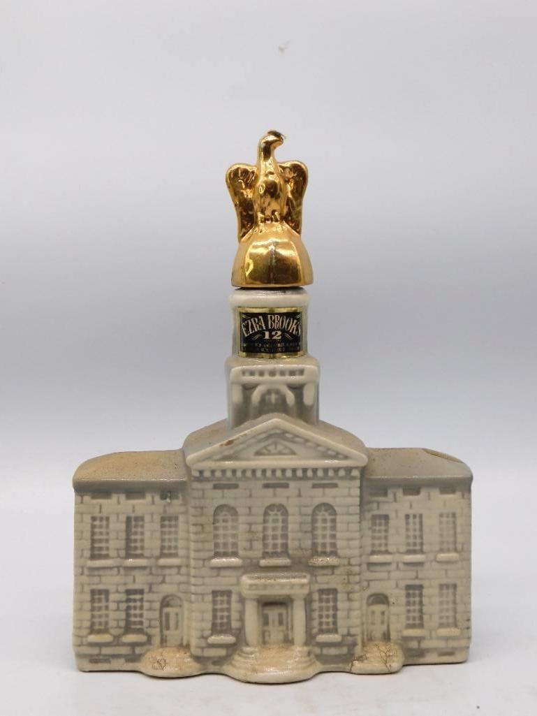 Ezra Brooks Statehouse Decanter with Gilt Eagle Stopper with Tax Strip: An Ezra Brooks decanter modeled as a stone statehouse its columned pediment and cupola carried up to a gilt eagle that serves as the stopper. The brickwork and window courses are crisply molded workma