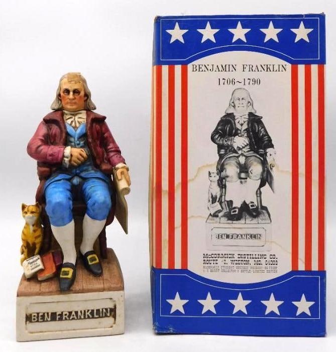 McCormick Benjamin Franklin 1706-1790 Decanter with Original Box: A McCormick bottle modeled as Benjamin Franklin seated with a scroll in hand his tabby cat at his feet beside a copy of the Almanack of 1733. The painter worked in a genial register of plum coat blue