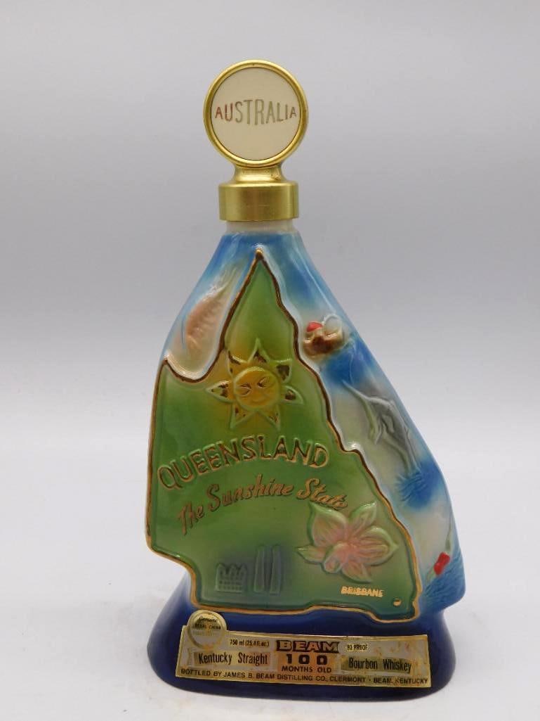 Jim Beam Queensland Australia Sunshine State Decanter: A Jim Beam decanter commemorating Queensland Australia the Sunshine State with the Brisbane skyline set among floral motifs and an Australia medallion stopper. Marked 100 Months Old Kentucky Straight 
