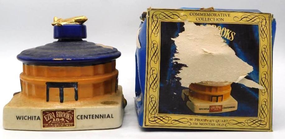 Ezra Brooks Wichita Centennial 1870-1970 Decanter with Original Box: An Ezra Brooks Heritage China decanter modeled as a domed Wichita landmark in cobalt and amber a gold airplane perched atop for a stopper. WICHITA CENTENNIAL runs boldly across the white plinth and th